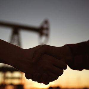 Handshake in front of an oil rig, symbolizing oil and gas lease agreements in West Virginia.