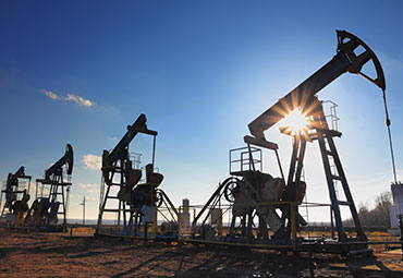 Oil & Gas Law – Oil pump jacks operating under a clear blue sky, representing legal matters in the energy sector.